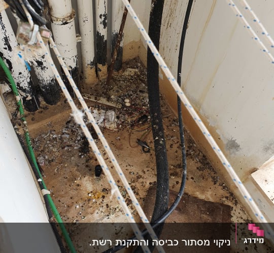 חבלים, צינורות ולכלוך על רצפה בפינת מבנה